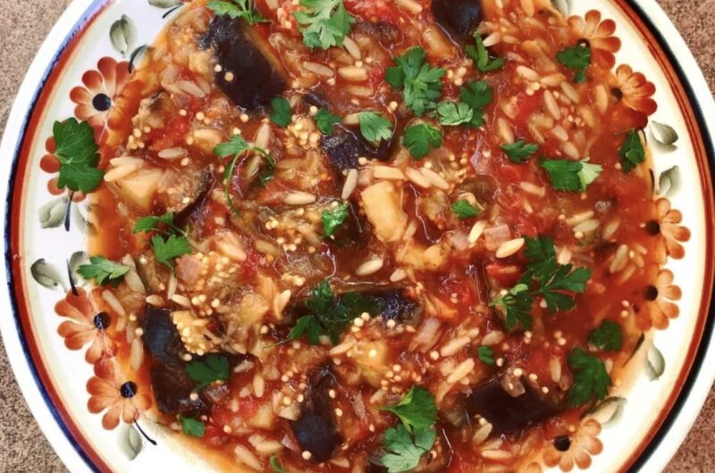 Drobno krojony bakłażan duszony razem z cebulą, pomidorami i świeżymi ziołami z dodatkiem makaronu kritharaki.