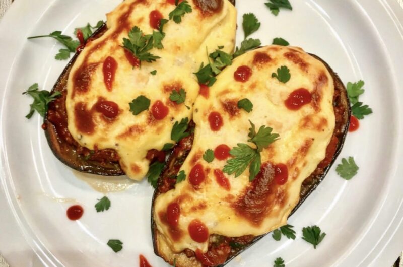 Przekrojony wzdłuż na połowę bakłażan pieczony, a następnie wypełniony aromatycznym duszonym mięsem i zapiekany pod pierzynką beszamelu.