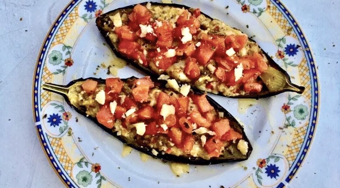 Przekrojony na połowę bakłażan pieczony, a następnie wymieszany z serem i pomidorami i zapiekany.