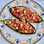 Przekrojony na połowę bakłażan pieczony, a następnie wymieszany z serem i pomidorami i zapiekany.