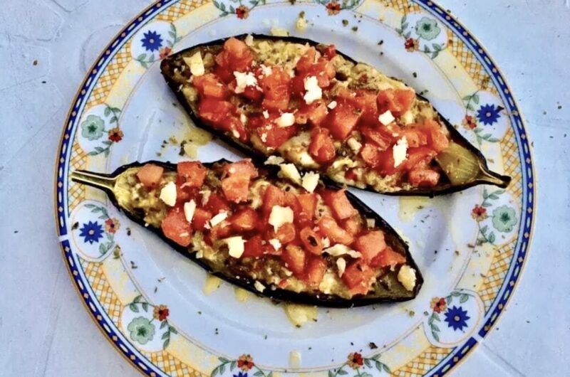 Przekrojony na połowę bakłażan pieczony, a następnie wymieszany z serem i pomidorami i zapiekany.