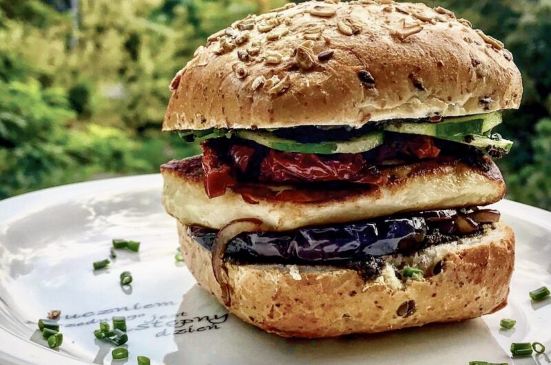 Burger wegetariański przygotowany na bazie tapenady z grillowanym serem halloumi, plastrami bakłażana, karmelizowaną cebulą a także z chrupiącymi warzywami.