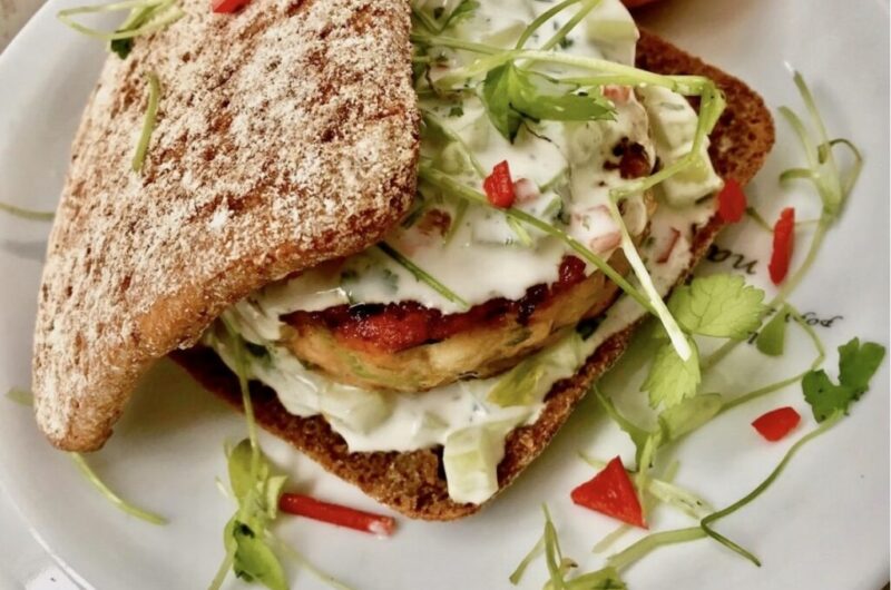 Burger z mielonego mięsa łososia i surowych krewetek doprawiony po azjatycku podany z dipem kolendrowym w świeżej bułce.