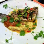 Dorada smażona, a następnie duszona z szafranem w przyprawie harissa z dymką, kiszoną cytryną, rodzynkami i suszonymi morelami.