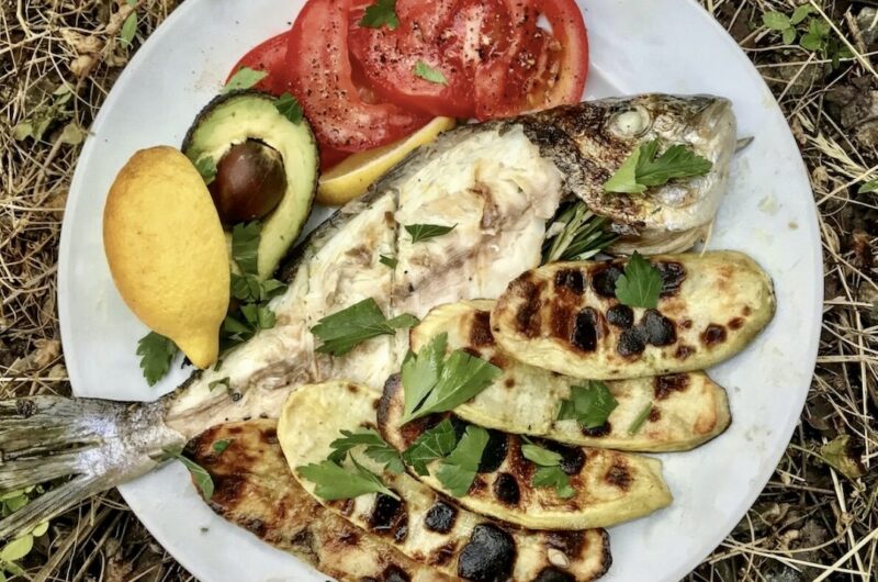 Dorada z grilla to ryba marynowana najpierw w oliwie z dodatkiem czosnku, a następnie wypełniona plastrami cytryny i świeżym rozmarynem i pieczona rna uszcie.