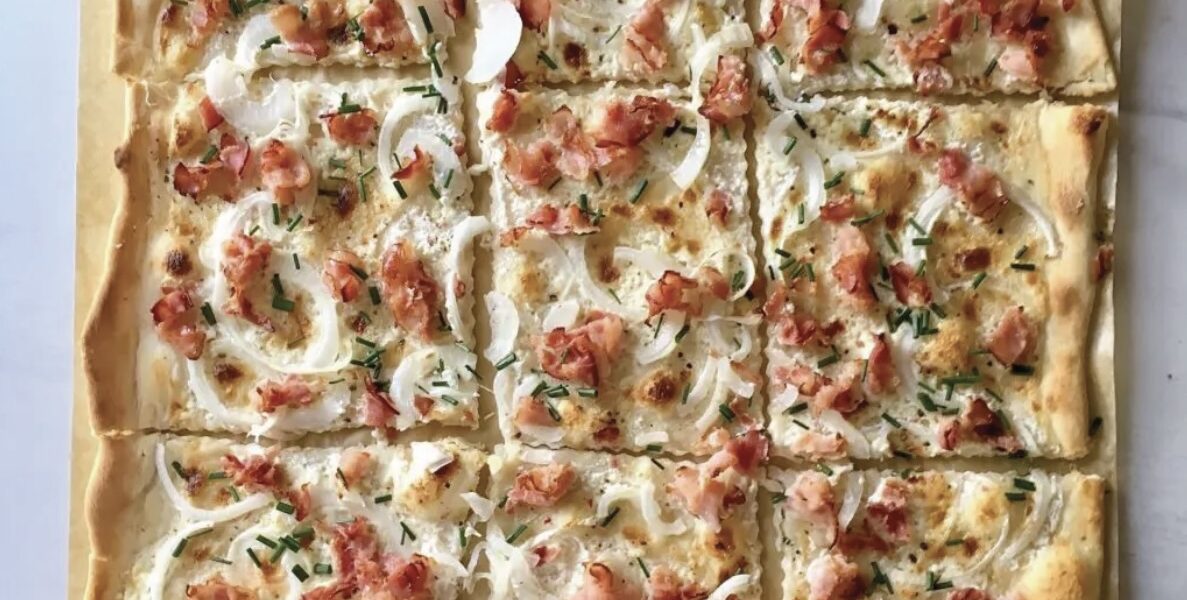 Flammkuchen alzacki to prosty podpłomyk przygotowany z mąki i wody. Na cieniutko rozwałkowane ciasto nakłada się śmietanę, a następnie piórka cebuli i plasterki wędzonego boczku. Pieczemy bardzo krótko w bardzo wysokiej temperaturze.