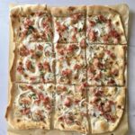 Flammkuchen alzacki to prosty podpłomyk przygotowany z mąki i wody. Na cieniutko rozwałkowane ciasto nakłada się śmietanę, a następnie piórka cebuli i plasterki wędzonego boczku. Pieczemy bardzo krótko w bardzo wysokiej temperaturze.
