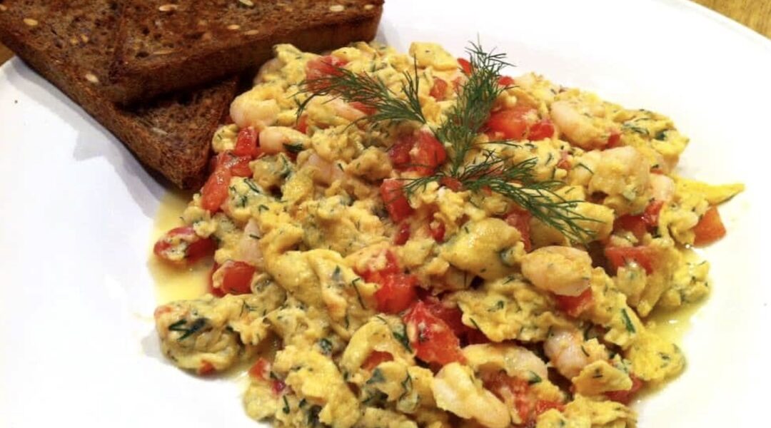 Jajecznica z krewetkami z dodatkiem drobno krojonych pomidorów i świeżego koperku.