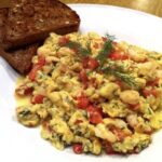 Jajecznica z krewetkami z dodatkiem drobno krojonych pomidorów i świeżego koperku.