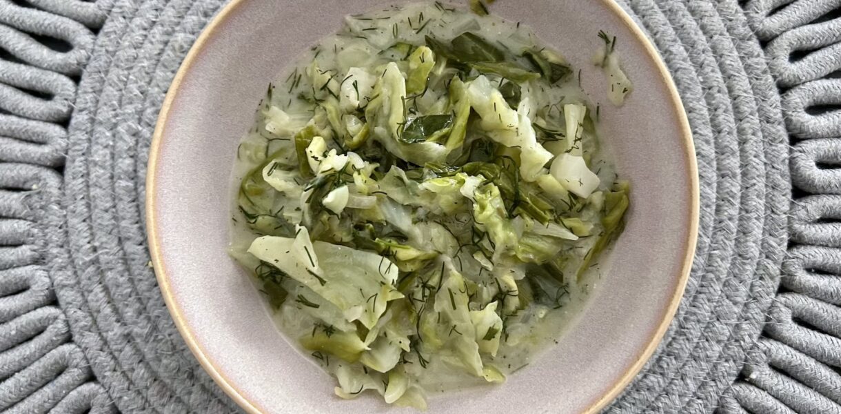 Młoda, drobno siekana i krótko gotowana słodka biała kapusta zasmażana na maśle, z dodatkiem świeżego koperku i kwaśnej śmietany.