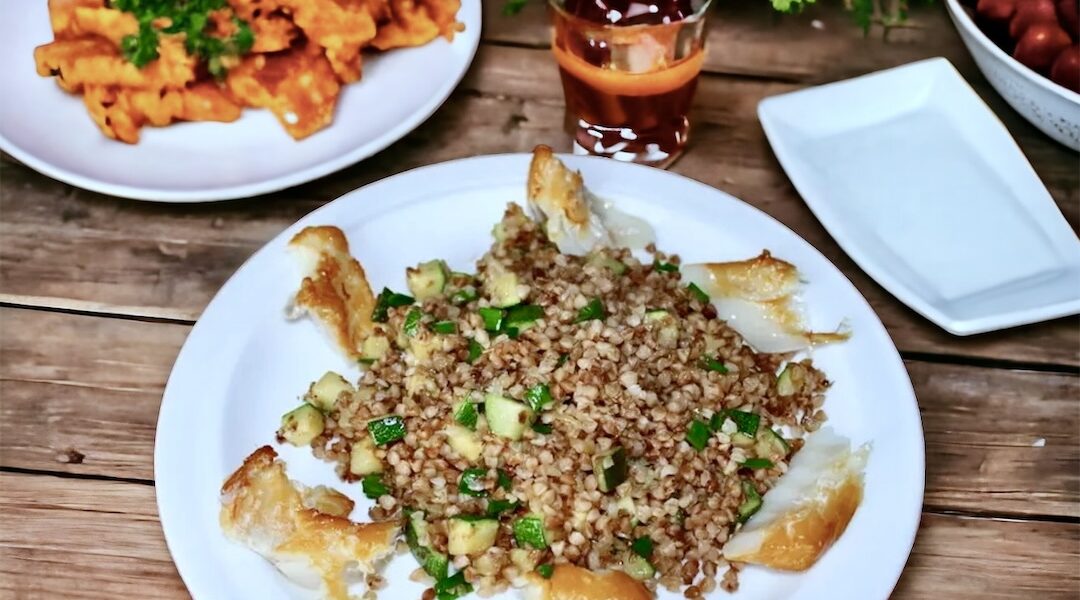 Ugotowana kasza gryczana podana z przesmażoną dymką i cukinią podana z wędzonym dorszem
