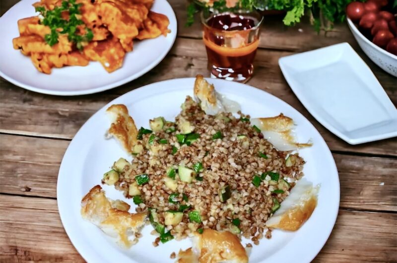 Ugotowana kasza gryczana podana z przesmażoną dymką i cukinią podana z wędzonym dorszem