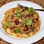 Kasza pęczak zmieszana z czerwoną fasolą, kukurydzą i papryką doprawiona sosami azjatyckimi podana na omlecie z jajek.