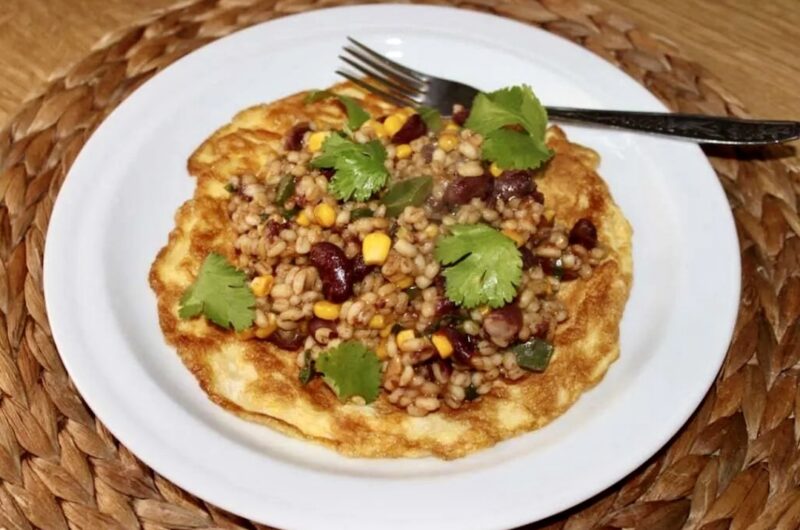 Kasza pęczak zmieszana z czerwoną fasolą, kukurydzą i papryką doprawiona sosami azjatyckimi podana na omlecie z jajek.
