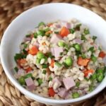 Ugotowana kasza pęczak podana z drobno krojoną szynką gotowaną oraz groszkiem i marchewką.