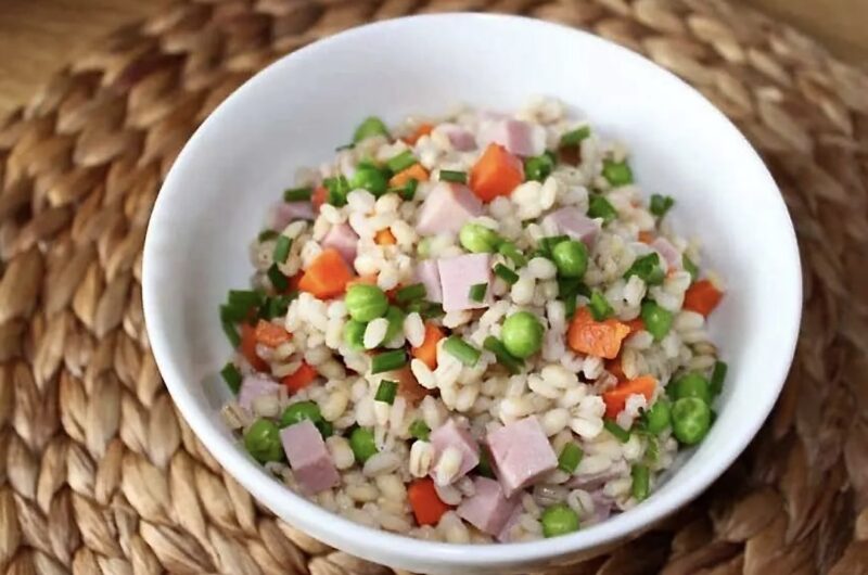 Ugotowana kasza pęczak podana z drobno krojoną szynką gotowaną oraz groszkiem i marchewką.