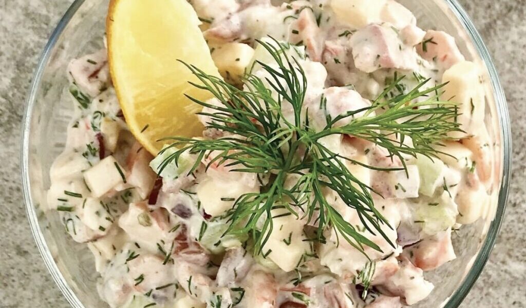 Koktajl z krewetek z dodatkiem świeżego ogórka, pomidora, czerwonej cebuli i żółtego sera połączone sosem z jogurtu greckiego i majonezu.