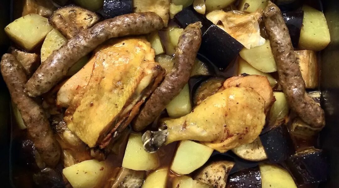 Kurczak z piekarnika z bakłażanem to kompletny posiłek składający się z pieczonych udek z kurczaka, kiełbasek wieprzowych oraz ziemniaków, bakłażana i główki czosnku.