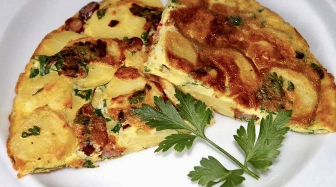 Omlet po śląsku, czyli omlet z dodatkiem plastrów ugotowanych ziemniaków i kawałków wędzonych kiełbasek wieprzowych oraz siekanej natki pietruszki.