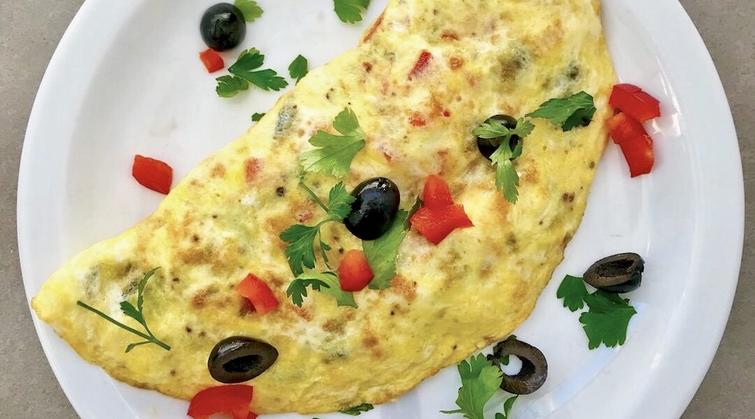 Omlet z łososiem wędzonym z dodatkiem oliwek, czerwonej papryki i startego parmezanu.