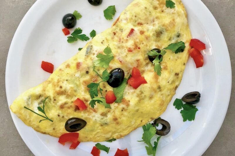 Omlet z łososiem wędzonym z dodatkiem oliwek, czerwonej papryki i startego parmezanu.