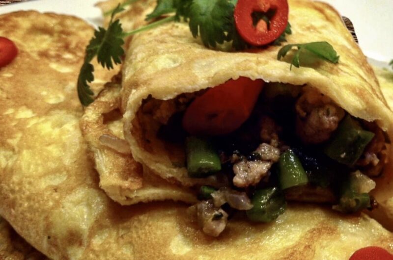 Omlet z wieprzowiną po tajsku to mielone mięso smażone razem z aromatyczną pastą z dodatkiem fasolki szparagowej, a następnie zawinięte w prosty omlet usmażony z rozkłóconych jajek