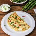 Omlet ze szparagami przyrządzamy zawsze ze świeżych wiejskich jajek. Rozkłócone jajka należy połączyć na patelni z kawałkami jędrnych zielonych szparagów oraz serem feta i ostrą papryczką chilli.