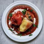 Papryka faszerowana kurczakiem to przekrojone na połowę papryki wypełnione farszem z kurczaka i ryżu, a następnie zapiekane i podane na sosie pomidorowym.