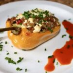 Przekrojona na połowę papryka faszerowana warzywami i kaszą z dodatkiem, a następnie zapiekana.