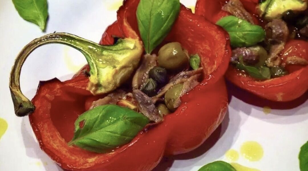 Papryka pieczona po piemoncku to czerwona papryka przekrojona wzdłuż na połowę, wypełniona filetami anchois, kaparami i oliwkami, a następnie zapieczona.