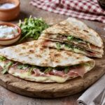 Piadina romagnola to nieduży włoski placek przyrządzany z mąki pszennej i smalcu. Po krótkim smażeniu piadinę wypełnia się ulubionymi składnikami i podgrzewa zajadając go jako sycącą przekąskę.