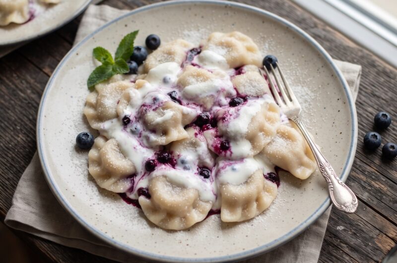 Pierogi wypełnione leśnymi borówkami z dodatkiem cukru gotowane i polane kwaśną śmietaną.