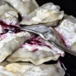Pierogi wypełnione leśnymi borówkami z dodatkiem cukru gotowane i polane kwaśną śmietaną.