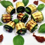 Roladki z cukinii przygotowujemy z plastrów świeżej cukinii. Cukinia pokrojona wzdłuż na plasterki najpierw powinna zostać grillowana. Później posmarowaną oliwą cukinię wypełniamy kawałkiem sera gorgonzola i suszonym pomidorem i zwijamy w roladkę.