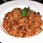 Ryż po majorkańsku oprócz ryżu zawiera w sobie także kaszankę i paprykowaną kiełbasę, a także pieczarki i pomidora. Całość na koniec należy posypać startym serem.