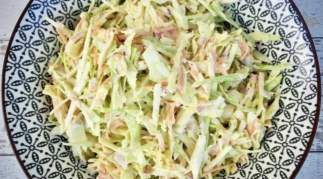 Sałatka vel surówka Coleslaw to pyszny dodatek do obiadu przygotowany z siekanej białej kapusty z dodatkiem startej marchewki doprawiony majonezem i jogurtem greckim.