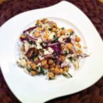 Sałatka z ciecierzycy z puszki z dodatkiem czerwonej cebuli i wędzonego dorsza skropiona oliwą extra vergine.