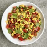 Sałatka z kukurydzą może być świetnym dodatkiem do niemal każdego posiłki. Przygotowana została ziaren kukurydzy gotowanej, posiekanych pomidorów, ostrych papryczek, dymki i świeżej kolendry, a przed podaniem skropiona sokiem z limonki i oliwą.