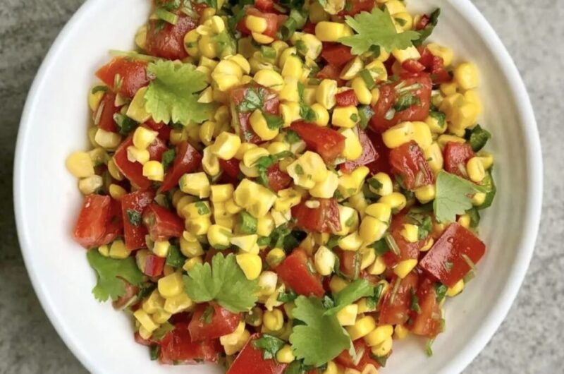 Sałatka z kukurydzą może być świetnym dodatkiem do niemal każdego posiłki. Przygotowana została ziaren kukurydzy gotowanej, posiekanych pomidorów, ostrych papryczek, dymki i świeżej kolendry, a przed podaniem skropiona sokiem z limonki i oliwą.