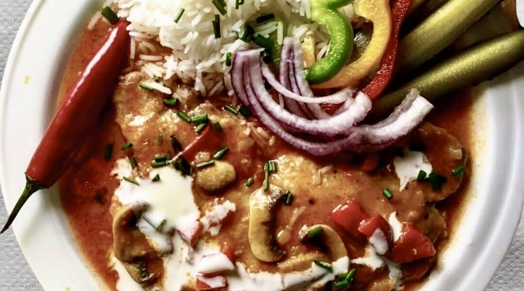 Schab po bakońsku, czyli kotlet schabowy duszony z cebulą, pomidorami, pieczarkami i dużą ilością słodkiej mielonej papryki doprawiony kwaśną śmietaną.