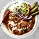 Schab po bakońsku, czyli kotlet schabowy duszony z cebulą, pomidorami, pieczarkami i dużą ilością słodkiej mielonej papryki doprawiony kwaśną śmietaną.