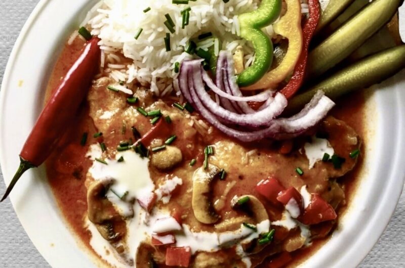 Schab po bakońsku, czyli kotlet schabowy duszony z cebulą, pomidorami, pieczarkami i dużą ilością słodkiej mielonej papryki doprawiony kwaśną śmietaną.