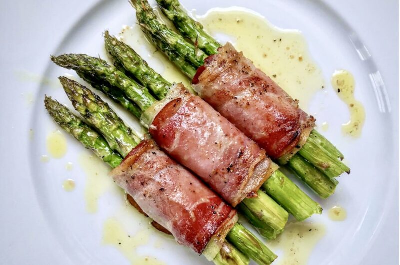 Zielone szparagi owinięte plastrami szynki dojrzewającej, pieczone i skropione oliwą extra vergine tuż przed podaniem.