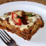 Zapiekanka z bakłażanem przekładanym aromatycznym mięsem mielonym w sosie pomidorowym od góry obłożona serem taleggio i ostrym chilli.