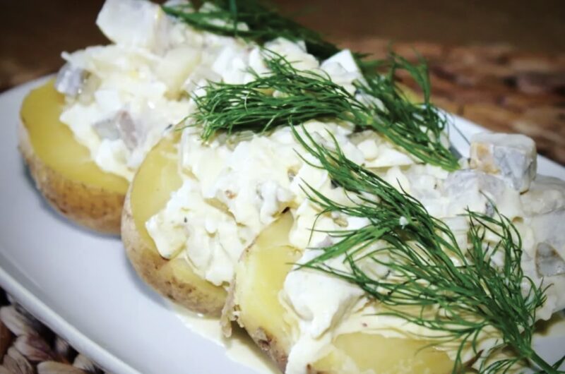 Gotowane ziemniaki podane z sałatką śledziową ze śledzia matiasa, ogórków kiszonych, jajka gotowanego i kwaśnej śmietany.