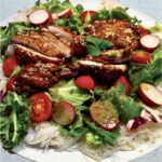 Azjatycka sałatka z orientalnie przyprawionym smażonym kurczakiem podanym na makaronie ryżowym z dodatkiem sałat i rzodkiewek oraz aromatycznego dipu.