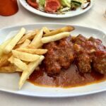 Klopsy mielone przyrządzone z wołowo-wieprzowego mięsa mielonego z dodatkiem bułki moczonej w winie oraz kminu rzymskiego, cynamonu i czosnku podane w sosie pomidorowym