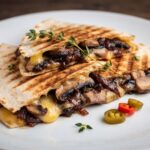 Quesadilla z pieczarkami czyli tortilla obłożona smażonymi pieczarkami, pysznie karmelizowaną cebulą oraz serem, a następnie przykryta drugą tortillą i zapieczona.