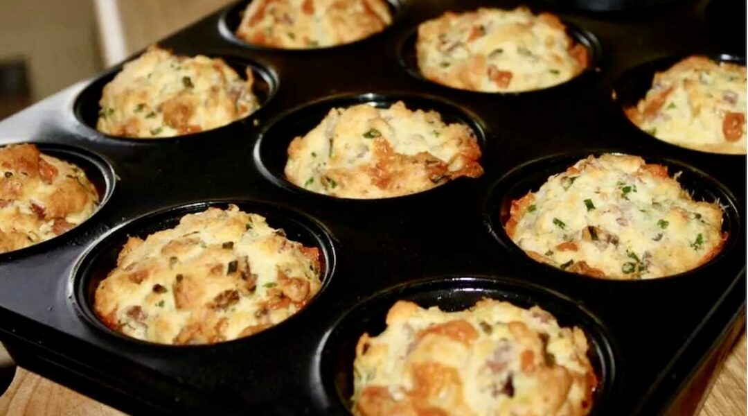 Babeczki na słono przygotowane z wędzoną szynką i twardym serem najpierw wyrobione z masłem, mlekiem, mąką i jajkami, a następnie pieczone w foremkach.