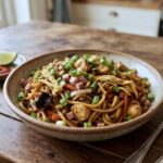 Bami Goreng to makaron wymieszany ze smażonymi kawałkami kurczaka, cebulą oraz warzywami, szynką i siekanym omletem.